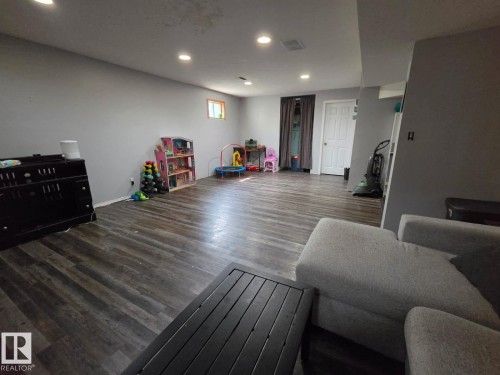 Spacious room featuring wood-finish flooring, recessed lighting, and a white paneled door - 3511 28 Avenue Nw, Edmonton, AB - Indoor