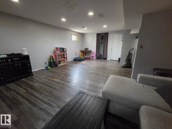 Spacious room featuring wood-finish flooring, recessed lighting, and a white paneled door - 