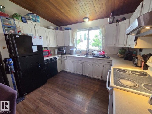 Kitchen featuring white cabinetry, wood-finish flooring, a white countertop, and a double-basin sink with a window above - 3511 28 Avenue Nw, Edmonton, AB - Indoor Photo Showing Kitchen With Double Sink
