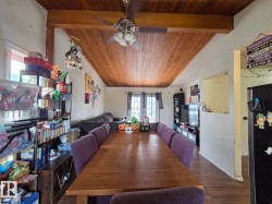 Vaulted wood-paneled ceiling with exposed wood beams, ceiling fan with attached lighting, and wood-finish flooring - 