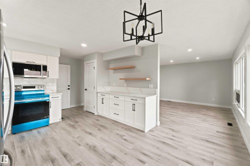 Kitchen featuring white cabinetry, wood-finish flooring, recessed lighting, and a modern geometric chandelier - 4129 134A Avenue Nw, Edmonton, AB - Indoor Photo Showing Kitchen