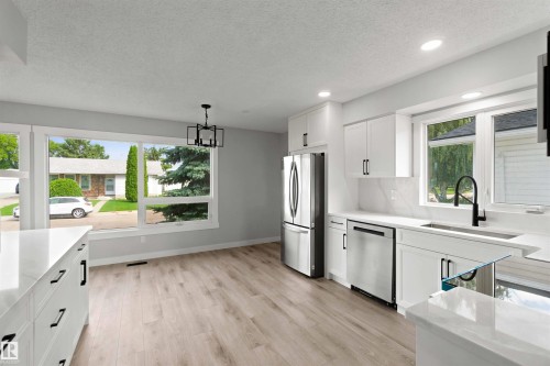 Contemporary kitchen featuring white cabinetry, stainless steel appliances, and a black matte faucet - 4129 134A Avenue Nw, Edmonton, AB - Indoor Photo Showing Kitchen With Upgraded Kitchen
