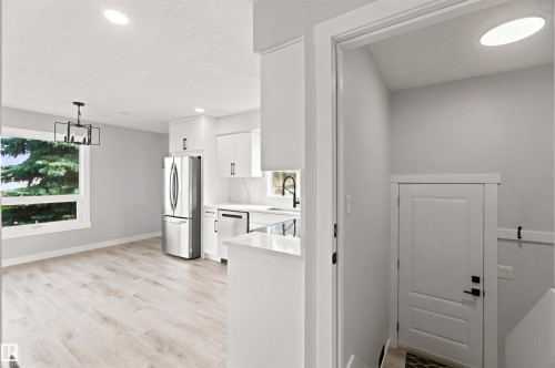 Contemporary kitchen with white cabinetry, stainless steel appliances, and light wood-finish flooring - 4129 134A Avenue Nw, Edmonton, AB - Indoor Photo Showing Kitchen