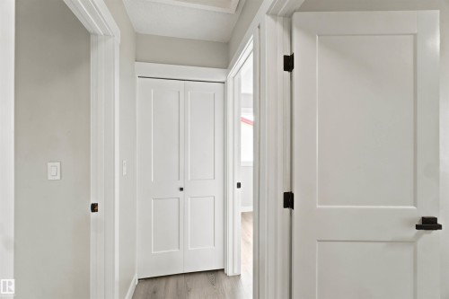 White paneled interior doors, bifold closet doors, and wood-finish flooring - 4129 134A Avenue Nw, Edmonton, AB - Indoor Photo Showing Other Room