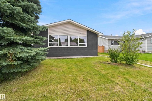 Exterior featuring dark brick and light-colored siding, a prominent front window, and a mature evergreen - 4129 134A Avenue Nw, Edmonton, AB - Outdoor