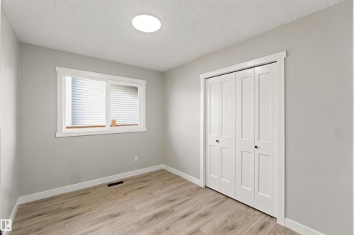 Light gray wall color, wood-finish flooring, white window trim, white bi-fold closet doors, and a ceiling-mounted light fixture - 4129 134A Avenue Nw, Edmonton, AB - Indoor Photo Showing Other Room