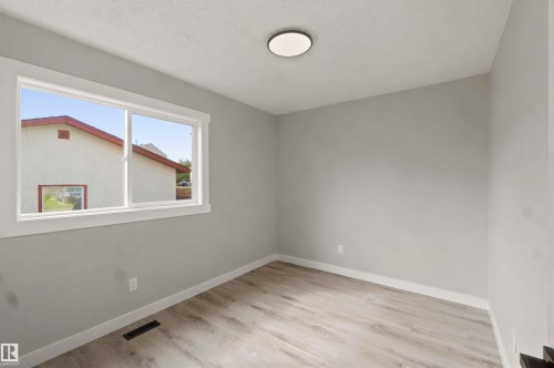 Neutral wall paint, wood-finish flooring, white window trim, and a flush-mount ceiling light - 4129 134A Avenue Nw, Edmonton, AB - Indoor Photo Showing Other Room