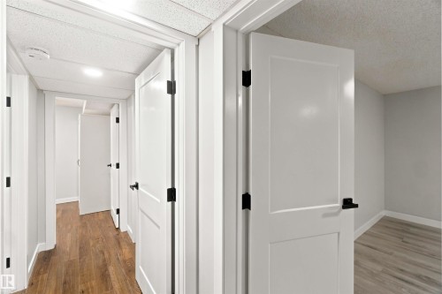 Hallway featuring wood-finish flooring, white paneled doors with black hardware, and recessed lighting - 4129 134A Avenue Nw, Edmonton, AB - Indoor Photo Showing Other Room