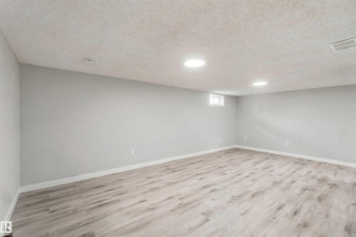 Spacious room featuring wood-finish flooring, light gray walls, and recessed ceiling lighting - 4129 134A Avenue Nw, Edmonton, AB - Indoor