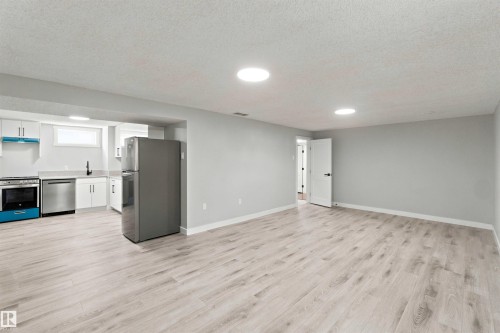 Light-toned wood-finish flooring throughout, recessed lighting, white perimeter cabinetry, stainless steel appliances, and a black wall-mounted faucet - 4129 134A Avenue Nw, Edmonton, AB - Indoor