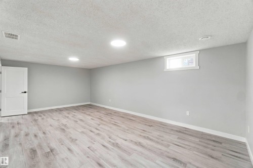 Spacious room featuring wood-finish flooring, light gray wall paint, white trim, and recessed ceiling lights - 4129 134A Avenue Nw, Edmonton, AB - Indoor