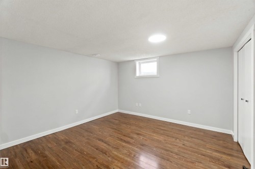 Light gray walls with wood-finish flooring, featuring a window and a ceiling-mounted light fixture - 4129 134A Avenue Nw, Edmonton, AB - Indoor Photo Showing Other Room