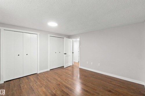 Wood-finish flooring, white bi-fold closet doors, recessed ceiling lighting, and a neutral wall color - 4129 134A Avenue Nw, Edmonton, AB - Indoor Photo Showing Other Room