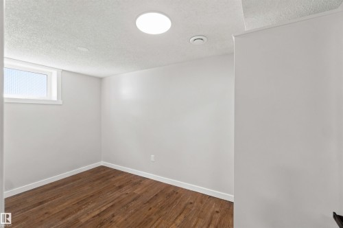 Wood-finish flooring with white trim, a recessed ceiling light, and a single window - 4129 134A Avenue Nw, Edmonton, AB - Indoor Photo Showing Other Room