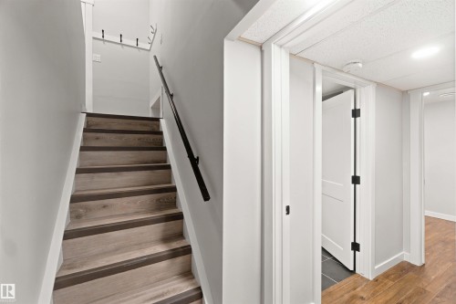 Wood-finish stairs with dark risers and a black handrail - 4129 134A Avenue Nw, Edmonton, AB - Indoor Photo Showing Other Room