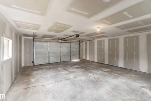 Spacious garage with an automatic overhead door, concrete flooring, and a single window - 4129 134A Avenue Nw, Edmonton, AB - Indoor Photo Showing Garage