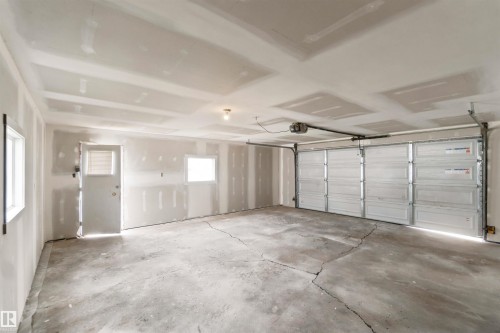 Concrete flooring, two windows, service door with window, overhead garage door, automatic garage door opener - 4129 134A Avenue Nw, Edmonton, AB - Indoor Photo Showing Garage