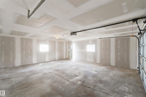 Spacious garage with concrete flooring, exposed drywall, and two windows - 4129 134A Avenue Nw, Edmonton, AB - Indoor Photo Showing Garage