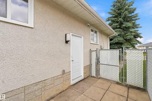 Stucco exterior with a stone veneer foundation, white framed windows, and a white exterior door - 4129 134A Avenue Nw, Edmonton, AB - Outdoor With Exterior