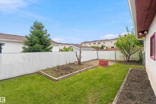 Expansive backyard with a manicured lawn, established perimeter fencing, and raised garden beds - 4129 134A Avenue Nw, Edmonton, AB - Outdoor
