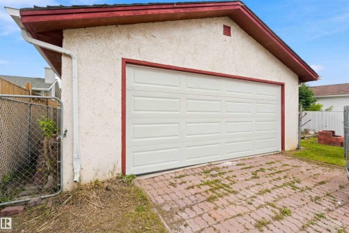 Detached garage with a paneled door, stucco exterior, red trim, and shingle roofing - 4129 134A Avenue Nw, Edmonton, AB - Outdoor With Exterior