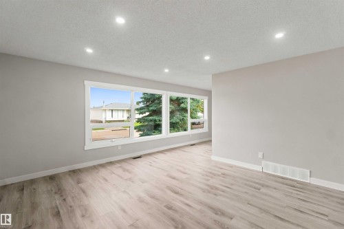 Recessed ceiling lighting, light-toned wall paint, wood-finish flooring, white trim, and a multi-pane window - 4129 134A Avenue Nw, Edmonton, AB - Indoor