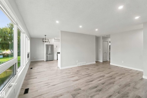 Expansive living area with wood-finish flooring, recessed lighting, and large windows - 4129 134A Avenue Nw, Edmonton, AB - Indoor Photo Showing Other Room