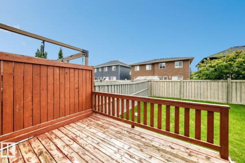Expansive outdoor deck with wood railing, leading to a fenced backyard with a lush lawn - 1112 176 Street Sw, Edmonton, AB - Outdoor With Exterior