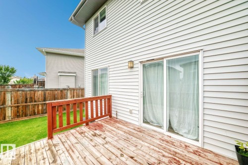 Wooden deck with a stained railing, white vinyl siding, sliding glass patio doors, and an exterior wall light - 1112 176 Street Sw, Edmonton, AB - Outdoor With Deck Patio Veranda With Exterior