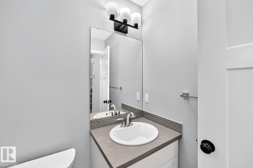 White vanity with a neutral countertop, undermount sink, chrome faucet, and subway tile backsplash - 1112 176 Street Sw, Edmonton, AB - Indoor Photo Showing Bathroom