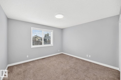 Neutral wall color palette, window with blinds, plush carpet flooring, white trim, and a ceiling-mounted light fixture - 1112 176 Street Sw, Edmonton, AB - Indoor Photo Showing Other Room