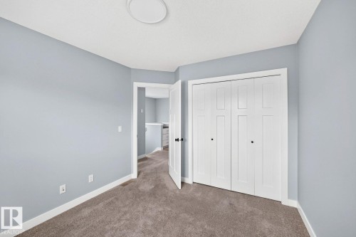 Carpeted flooring, light blue wall paint, white trim, white bi-fold closet doors, and a ceiling-mounted light fixture - 1112 176 Street Sw, Edmonton, AB - Indoor