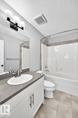White vanity with a gray countertop, an undermount sink, and chrome fixtures - 1112 176 Street Sw, Edmonton, AB - Indoor Photo Showing Bathroom