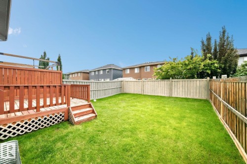 Expansive backyard with a manicured lawn, multi-level wood deck, wood privacy fencing, and mature trees - 1112 176 Street Sw, Edmonton, AB - Outdoor With Backyard