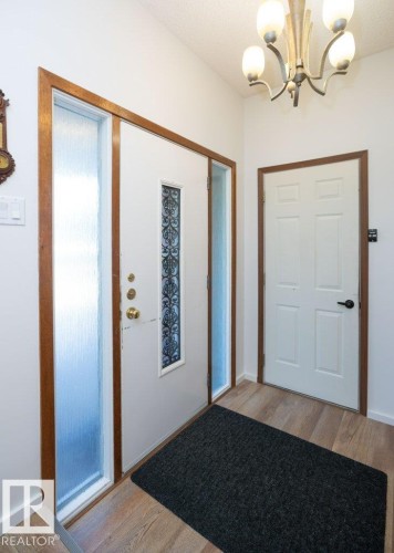 Entryway featuring a decorative front door with side lites, wood-finish flooring, and a multi-arm ceiling light fixture - 10729 108A Avenue, Westlock, AB - Indoor Photo Showing Other Room