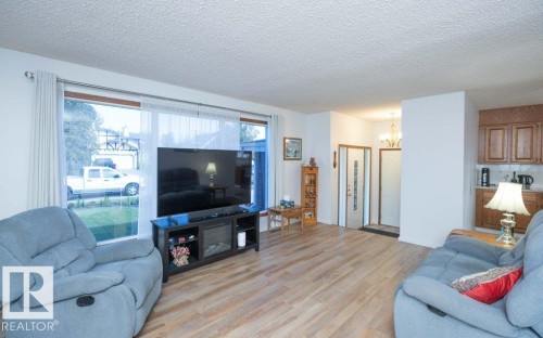Wood-finish flooring throughout, with a large picture window and an entryway featuring a paneled door - 10729 108A Avenue, Westlock, AB - Indoor Photo Showing Living Room