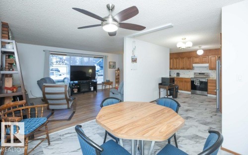 Combined living and dining area featuring a ceiling fan, wood-finish flooring, and a kitchen with wood cabinetry - 10729 108A Avenue, Westlock, AB - Indoor