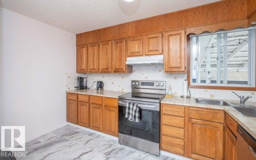Warm wood cabinetry with raised-panel doors and ample storage throughout this galley-style kitchen - 10729 108A Avenue, Westlock, AB - Indoor Photo Showing Kitchen