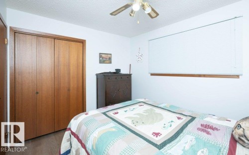Built-in wood-finish closet, horizontal window blinds, and overhead ceiling fan with integrated lighting - 10729 108A Avenue, Westlock, AB - Indoor Photo Showing Bedroom