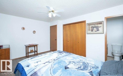 Wood-finish flooring, ceiling fan with light fixture, light wood-tone doors, and white walls - 10729 108A Avenue, Westlock, AB - Indoor Photo Showing Bedroom