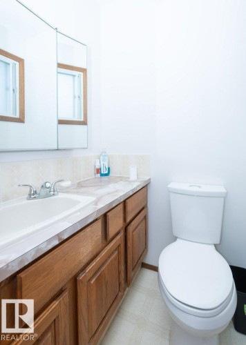 Light-toned cabinetry with a built-in sink, a light-toned countertop, and a mirrored medicine cabinet - 10729 108A Avenue, Westlock, AB - Indoor Photo Showing Bathroom