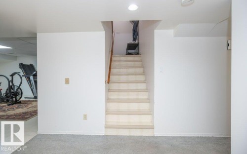 Carpeted staircase with wood-finish handrail, recessed lighting, and light gray carpet flooring - 10729 108A Avenue, Westlock, AB - Indoor Photo Showing Other Room