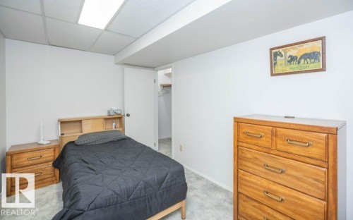 Recessed ceiling lighting, white acoustic ceiling tiles, light-colored walls, and a closet with an open doorway - 10729 108A Avenue, Westlock, AB - Indoor Photo Showing Bedroom