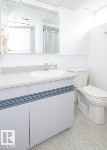 White vanity with an integrated sink, three-door mirrored medicine cabinet, and white toilet - 10729 108A Avenue, Westlock, AB - Indoor Photo Showing Bathroom