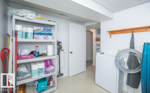 Laundry area featuring a front-loading washing machine, dedicated shelving, and a wall-mounted coat rack - 10729 108A Avenue, Westlock, AB - Indoor