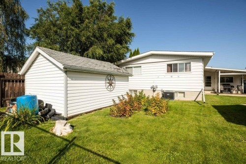 Expansive green lawn with a detached storage shed, white siding, and a covered patio area - 10729 108A Avenue, Westlock, AB - Outdoor
