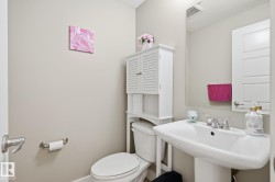 Pedestal sink with chrome faucet, toilet with overhead storage cabinet, and large wall-mounted mirror - 