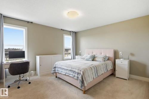 Soft neutral wall paint, carpeted flooring, two windows with curtain rods, and a ceiling-mounted light fixture - 944 Morris Way, Leduc, AB - Indoor Photo Showing Bedroom