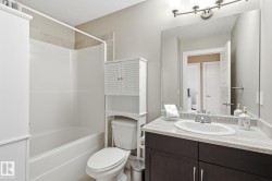Bathroom featuring a tub/shower combination with tile surround, a dark wood-finish vanity with an integrated sink, a light-toned countertop, and a wall-mounted mirror - 