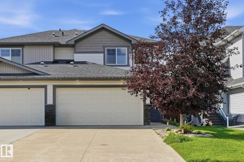 Two-story residence featuring light and dark gray siding, a concrete driveway, and a two-car garage - 944 Morris Way, Leduc, AB - Outdoor